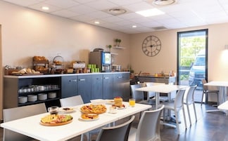 A breakfast area with tables, chairs, a clock, and a view of the outside.