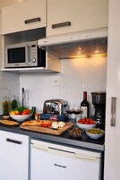A compact kitchen with a Linke microwave, a toaster, a coffee maker, and a Brandt refrigerator.