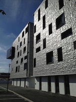 A modern building with a textured facade, multiple windows, and a flat roof.