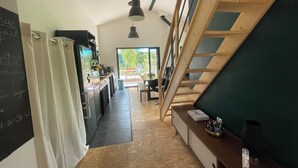 Una cocina con escalera de madera, comedor y vistas a través de un ventanal.