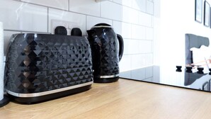 Una cocina de diseño moderno, con una cafetera negra y un hervidor sobre una encimera de madera.