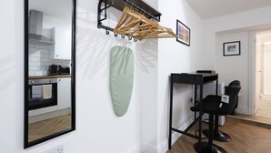 Una cocina con un espejo, un tendedero, una toalla verde y una silla negra.