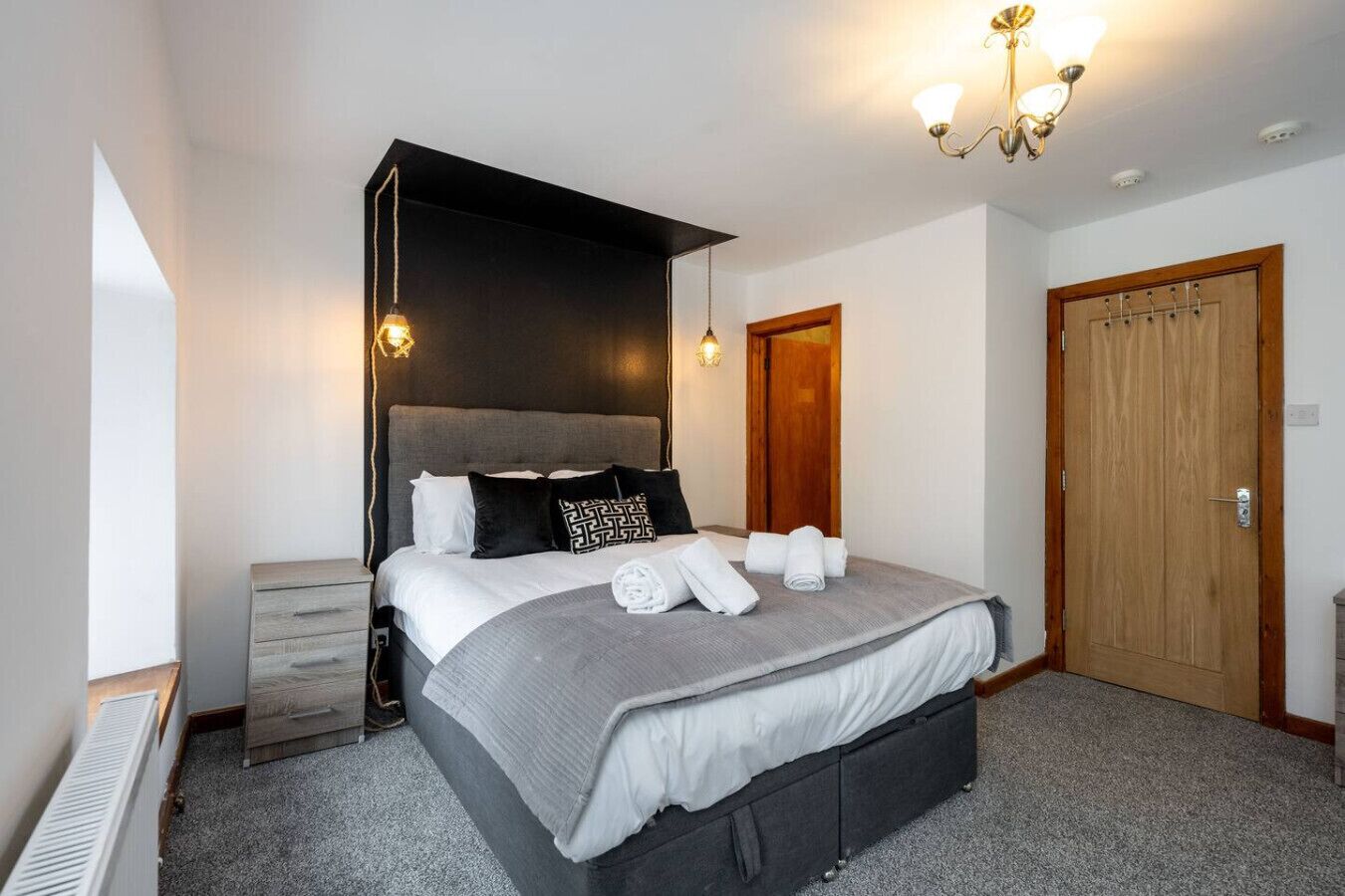 Une chambre à coucher comprenant un lit, des tables de chevet, une armoire et un lustre.