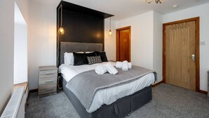 Un dormitorio con cama, mesitas de noche, armario y candelabro.