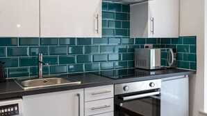 Una cocina moderna con armarios blancos, encimera negra, pileta de acero inoxidable, microondas y horno.