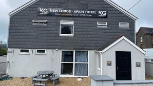 Un edificio de dos pisos con un cartel que dice 'KG New Lodge - Apart Hotel'.