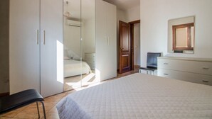 A bedroom with a bed, a wardrobe, a chair, and a desk. - GuestHost - A bright and welcoming 68 square meters apartment, perfect for four people, with a private entrance on the ground floor.The property is located in a quiet area of ​​Olbia and is close to all the main amenities, including restaurants, bars (Olbia)