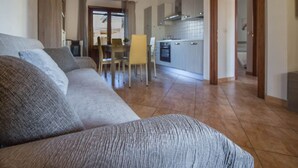 A living room with a sofa, a dining table with chairs, a kitchen area, and a hallway. - GuestHost - A bright and welcoming 68 square meters apartment, perfect for four people, with a private entrance on the ground floor.The property is located in a quiet area of ​​Olbia and is close to all the main amenities, including restaurants, bars (Olbia)