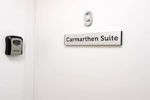 A door with a digital lock and a sign indicating 'Carmarthen Suite' and the number '9'.