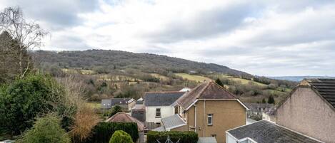 A residential area with houses, a hill in the background, and a cloudy sky.