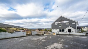 A building named 'The New Lodge' with a flat roof, a gated entrance, and a paved parking area.