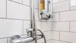 Et forkromet brusehoved med et fleksibelt brusearmatur, en vægmonteret reguleringsknop og et separat håndholdt brusehoved.