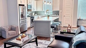 A modern kitchen with white cabinets, a central island, and stainless steel appliances. - Urban Escape in the heart of Downtown Houston (Houston)