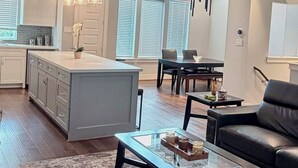 A modern kitchen with a central island, dining area with a table and chairs, and a living room with a sofa and coffee table. - Urban Escape in the heart of Downtown Houston (Houston)