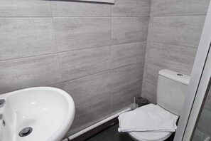 A bathroom with a white sink, toilet, and shower area.