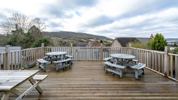 A wooden deck with picnic tables and a view of a hilly landscape. - Single Room • Fridge • Microwave • Parking (Pontardawe)