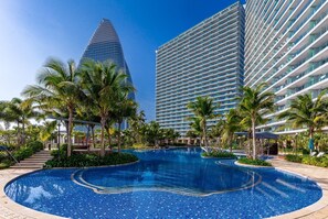 A swimming pool surrounded by palm trees and modern buildings. - YanShe Oceanview Resort Haitang Bay (Sanya)