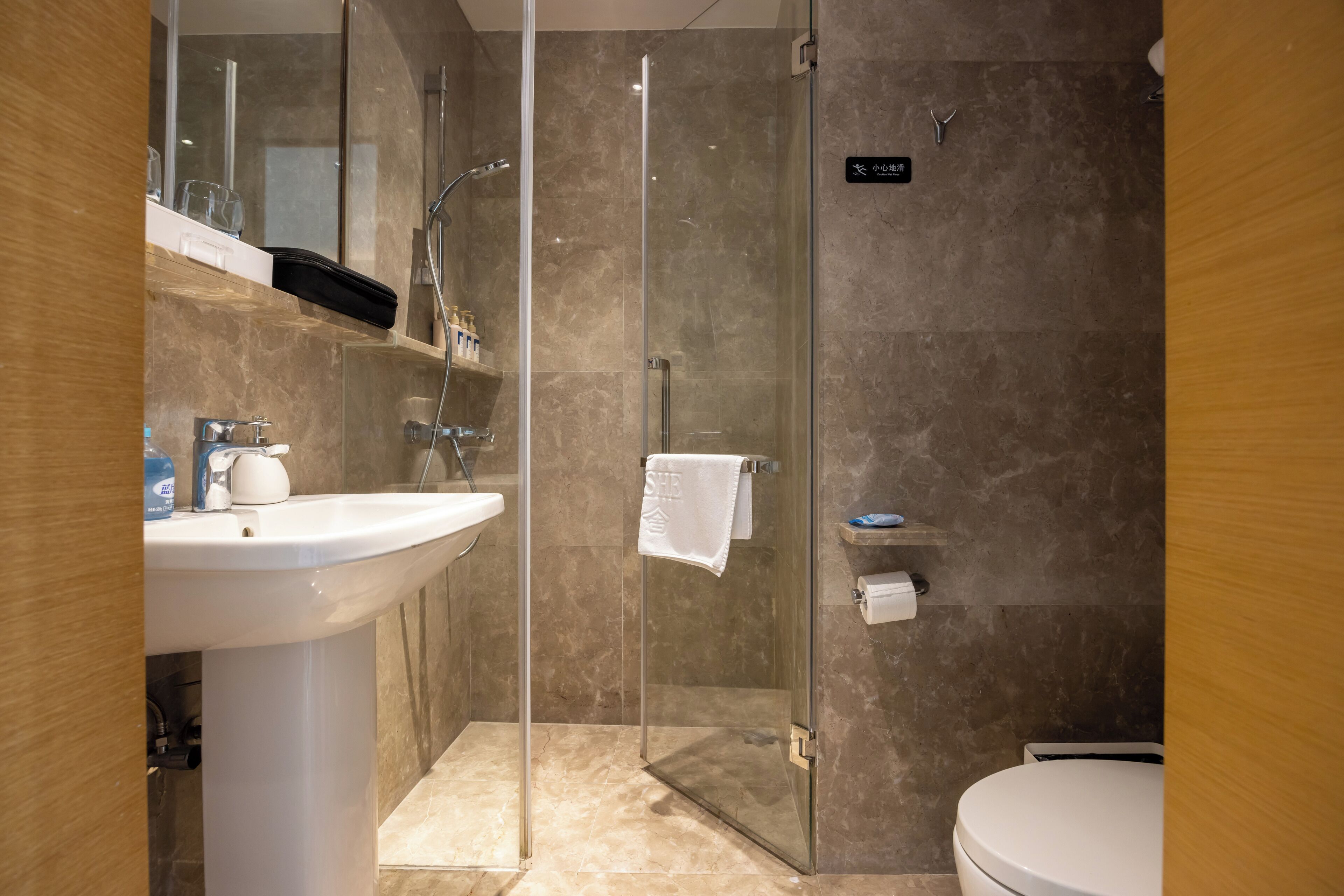 Een moderne badkamer met een douche met glazen wand, een wit wastafelmeubel en een toilet.