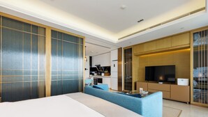 A modern hotel room with a large bed, a sofa, a TV, and a kitchenette. - YanShe Oceanview Resort Haitang Bay (Sanya)