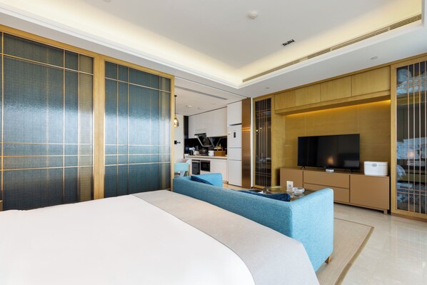 Une chambre d’hôtel moderne équipée d’un grand lit, d’un canapé, d’une télévision et d’une kitchenette.