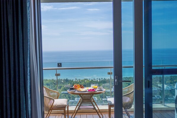 Balcón con mesa dispuesta para el desayuno, con vistas a la costa.