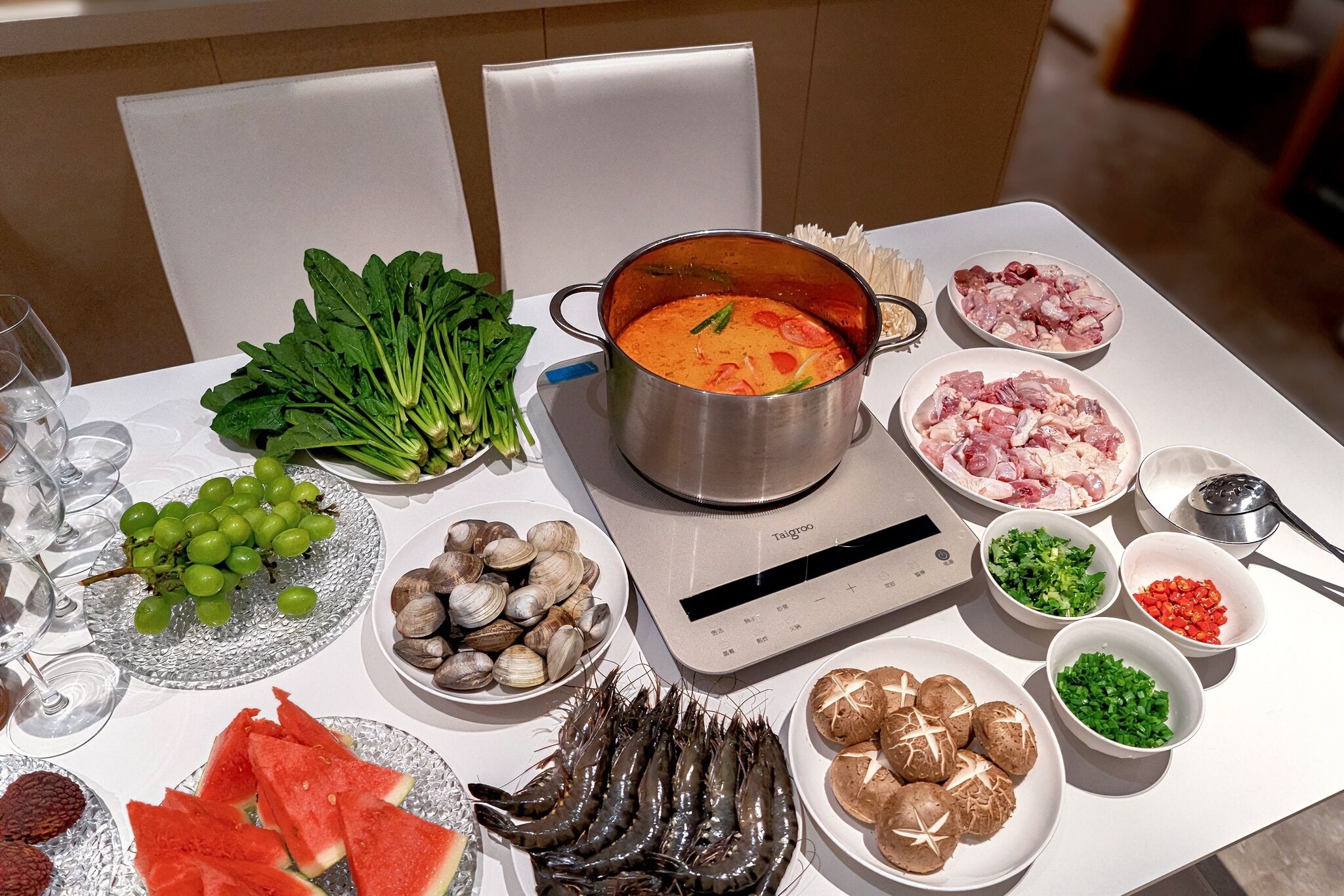 Et bord med forskellig mad, en gryde suppe, en vægt og et glas vand.
