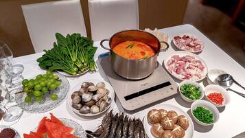 Et bord med forskellig mad, en gryde suppe, en vægt og et glas vand.