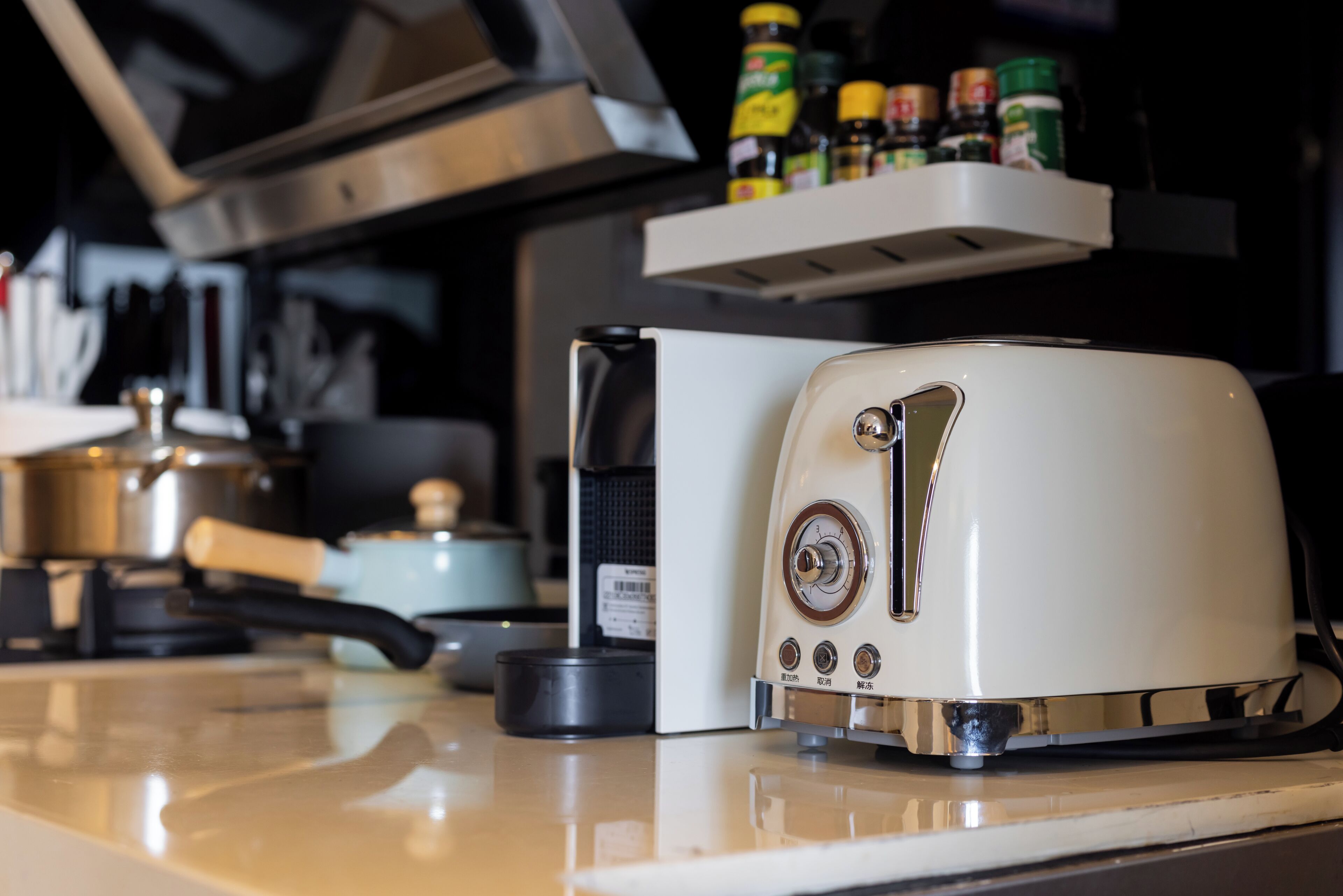 A kitchen with a white toaster, a coffee maker, and a shelf with various condiments.
