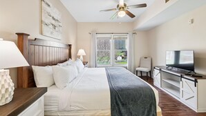 Une chambre à coucher avec un lit, une télévision, un ventilateur de plafond et une fenêtre donnant sur un beau paysage.