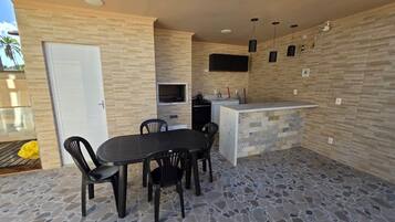 Un patio con una mesa y sillas, una pequeña cocina con microondas y una puerta.