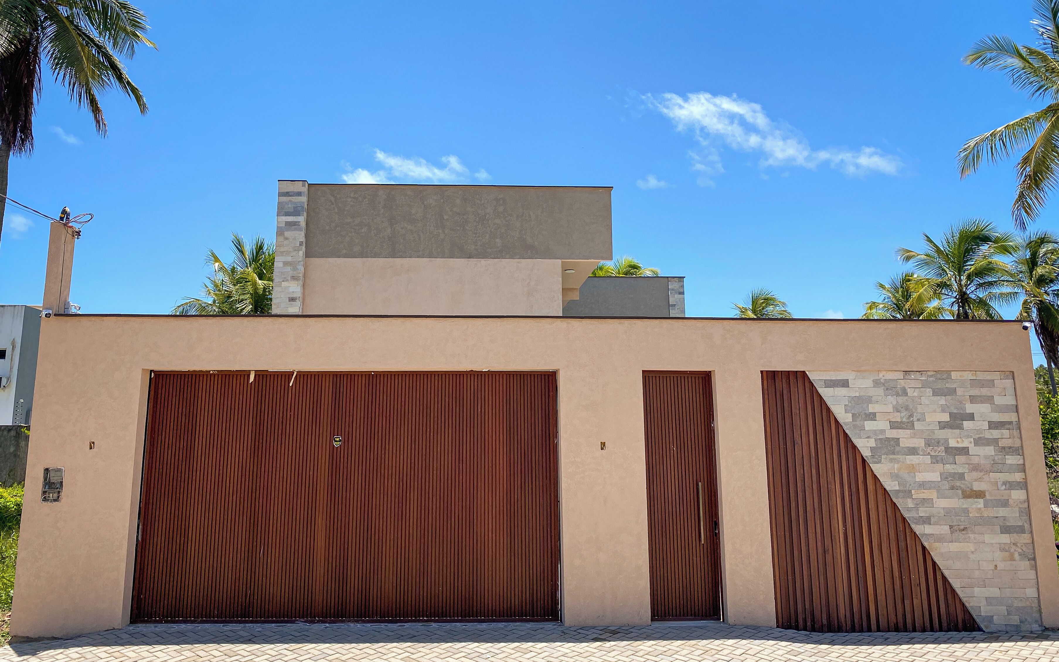 Un edificio moderno con una puerta de garaje grande, techo plano y una pared de ladrillo decorativa.