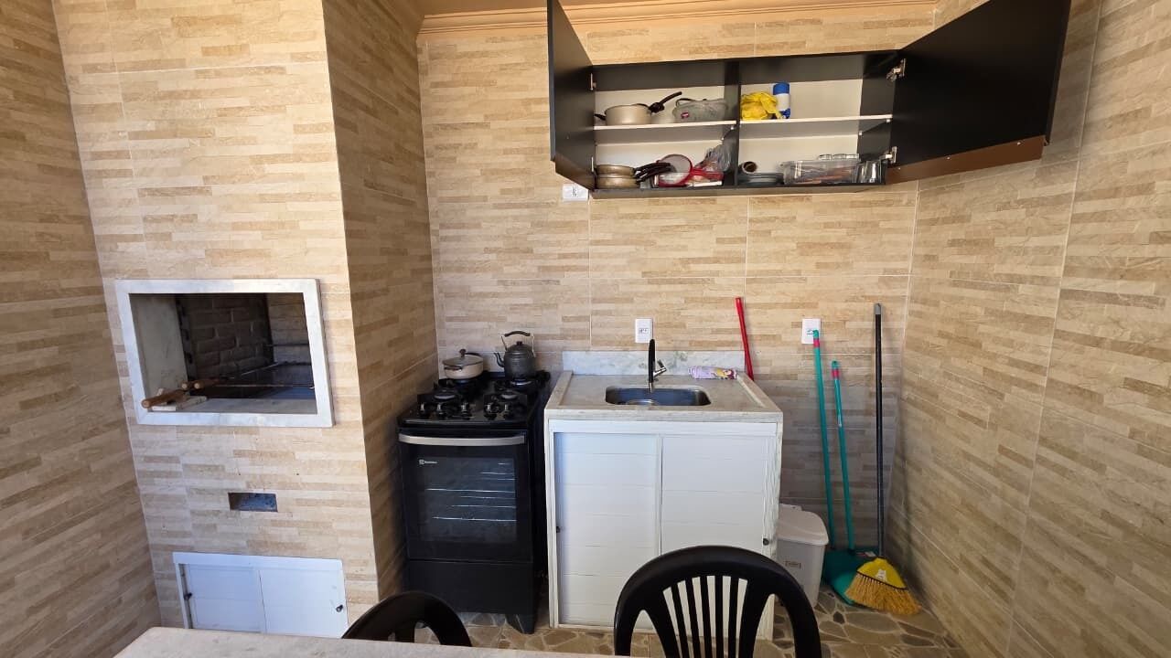 A compact kitchen with a gas stove, a small oven, a sink, and a broom.