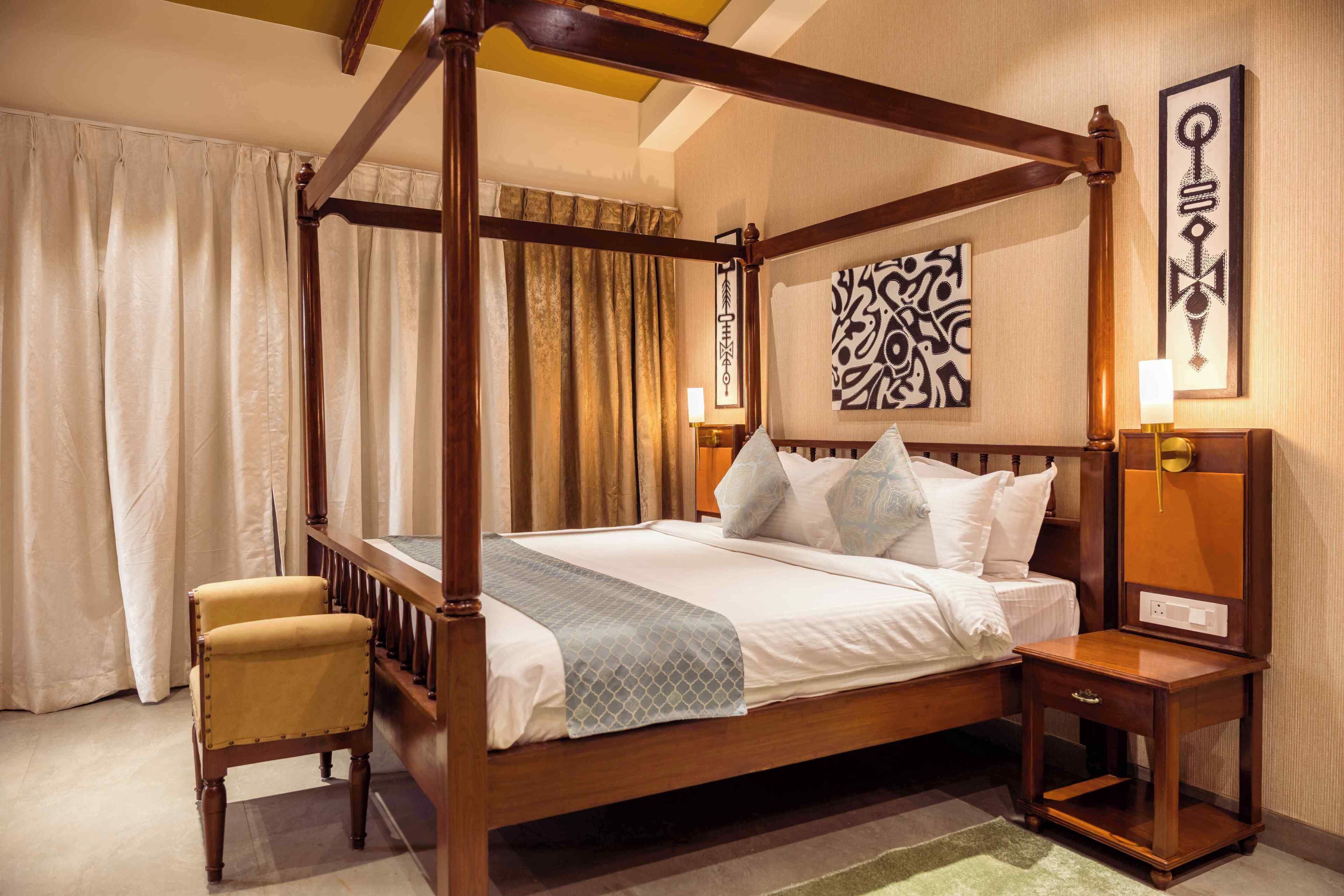 A four-poster bed with a wooden frame, a bedside table with a lamp, and a chair.
