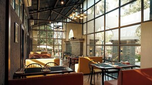 A restaurant with high ceilings, large windows, and a mix of seating arrangements including booths and tables. - Parkwood Exotica Resort (Alibag)