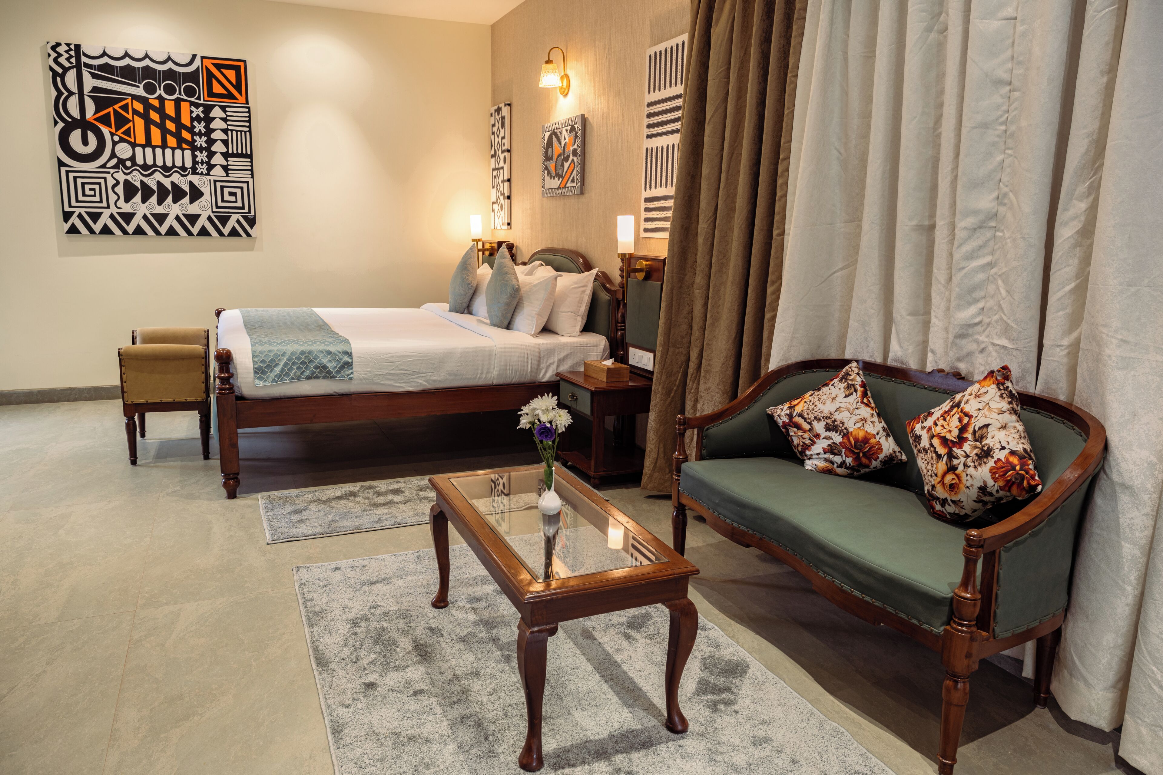 Una habitación de hotel con cama, sofá, mesa de centro y obras de arte en las paredes.