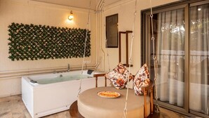 A room with a swing chair, a bathtub, and a wall-mounted decorative panel. - Parkwood Exotica Resort (Alibag)