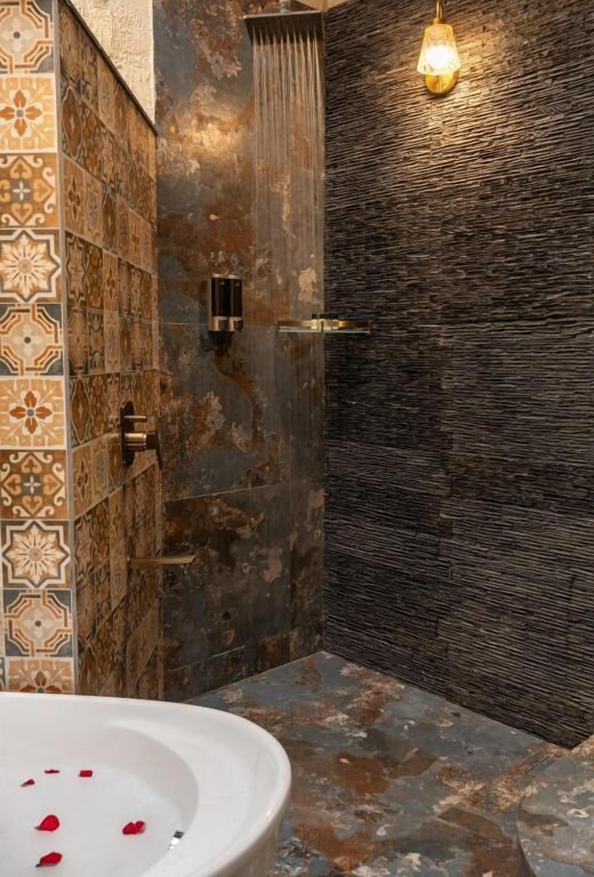 A bathroom with a shower, a sink with rose petals, and patterned tiles.