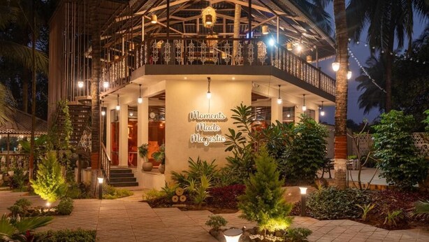 A two-story building with a balcony, a sign reading 'Moments Made Magestic,' and a well-lit outdoor area with plants. - Parkwood Exotica Resort (Alibag)
