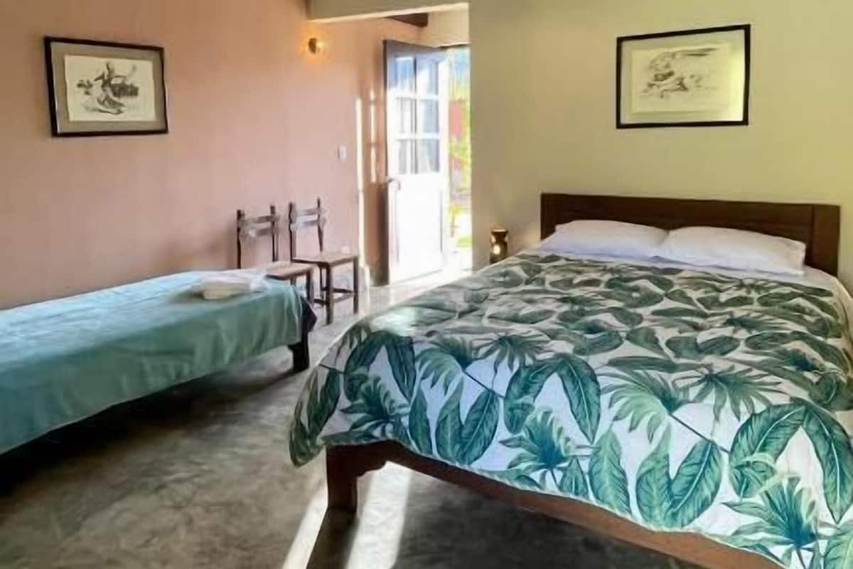 Ein Zimmer mit zwei Einzelbetten, Holzbalken an der Decke und gerahmten Kunstwerken an den Wänden.