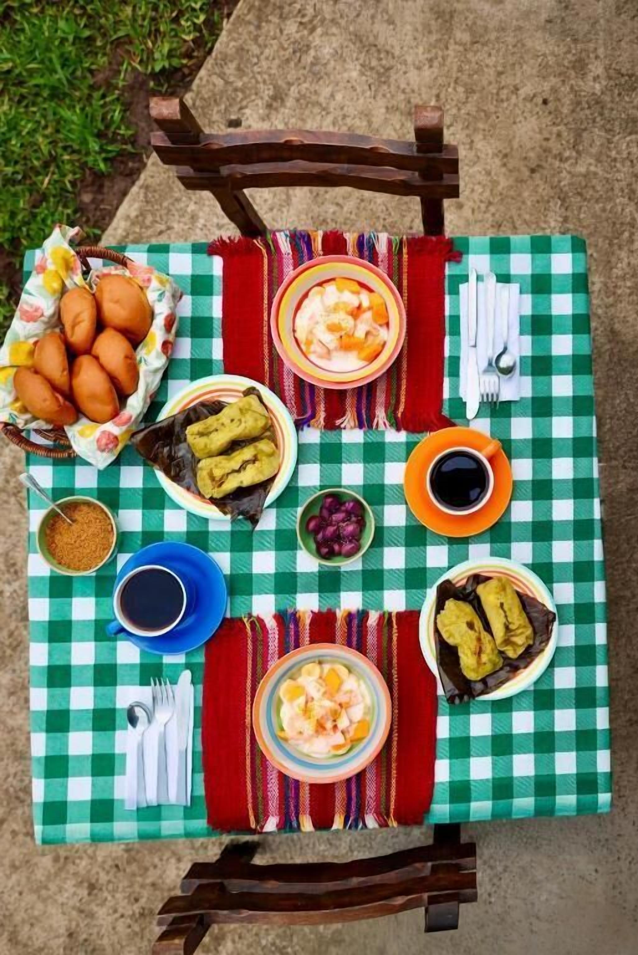 Una mesa dispuesta con diferentes platos, cubiertos y un mantel a cuadros.