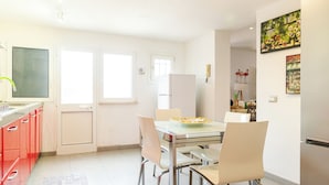 Eine moderne Küche mit Esstisch, Stühlen und einem Kühlschrank.