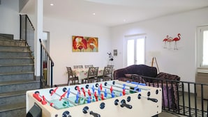 Ein Wohnzimmer mit Tischfußball, einer Treppe, einem Essbereich und einem Sofa.
