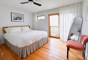 Ein Schlafzimmer mit Bett, Sessel, Deckenventilator, Fenster und Tür.