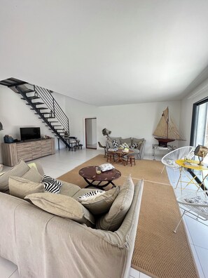 A modern living room with a staircase, a sofa, a coffee table, and a dining area. - Villa Corse du Sud Direct Access Lavu Santu Beach (Zonza)