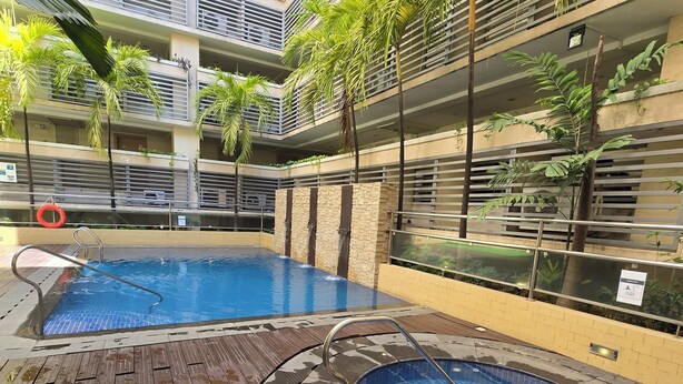 Ein mehrgeschossiges Gebäude mit Poolbereich, inklusive zweier Whirlpools und einer Holzterrasse.
