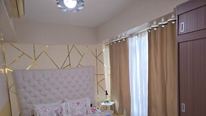 Ein ordentlich eingerichtetes Schlafzimmer mit einem gesteppten Kopfteil, floralem Bettzeug, einem Nachttisch mit Lampe und einem Kleiderschrank.