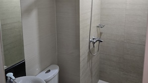 Ein Badezimmer mit Toilette, Waschbecken, Dusche und Spiegel.