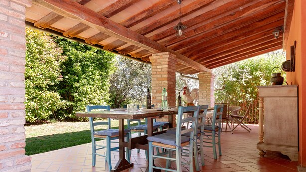 Eine Terrassengruppe mit Backsteinwand, Holztisch und Stühlen.