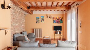Ein Wohnzimmer mit Sofa, Fernseher, Kamin und Bildern an den Wänden.