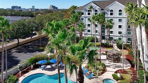 Un hotel con piscina, palmeras y vistas de la ciudad.